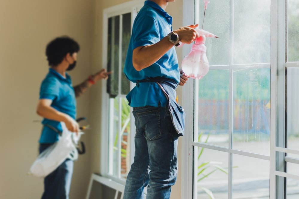 Window Cleaning. Unidentified worker wrapper tinting a window using foggy spray.