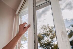 Trusted window cleaning specialists in Vancouver One sided open window. A hand opens a vinyl plastic window on a blue sky background.