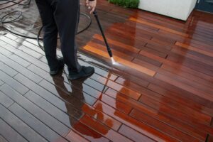 Why Vancouver Residents Trust Us for Pressure Washing Services. Deck pressure washing with a power washer, wood planks cleaning.