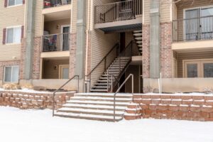 When Should Strata Managers Schedule Snow Removal? Main building entrances. Flight of stairs and balconies viewed at the facade of a residential building.